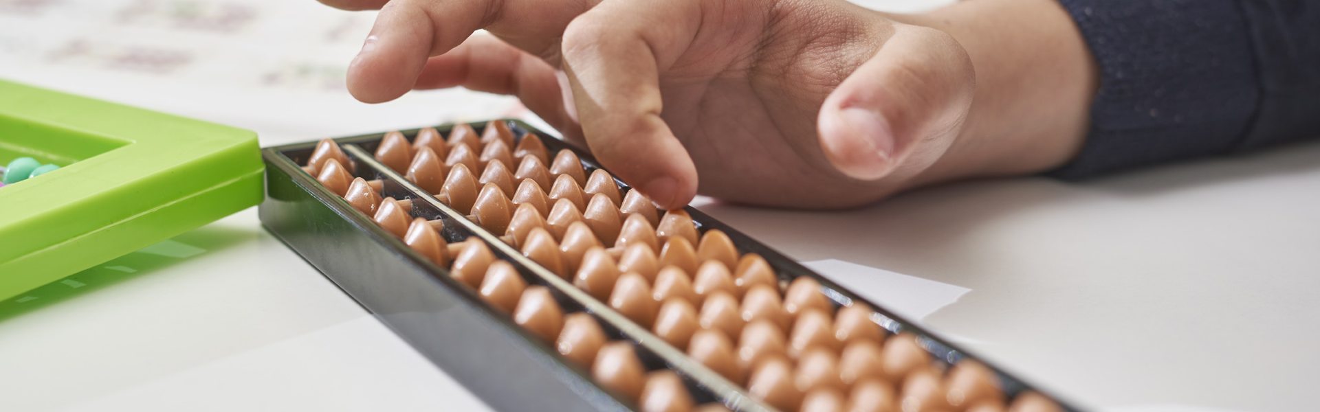 Doing mental math or mental arifmethic Doing mental math or mental arithmetic. Hand of little boy using abacus for calculating. Learning to use abacus on mental math courses. A kid doing math at home with abacus